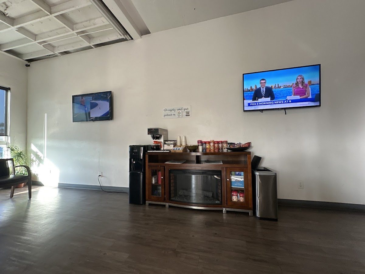 Two TVs above the coffee and snack console in the waiting room